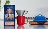 Alma Coffee package with a red mug and blue butter dish on a kitchen counter.