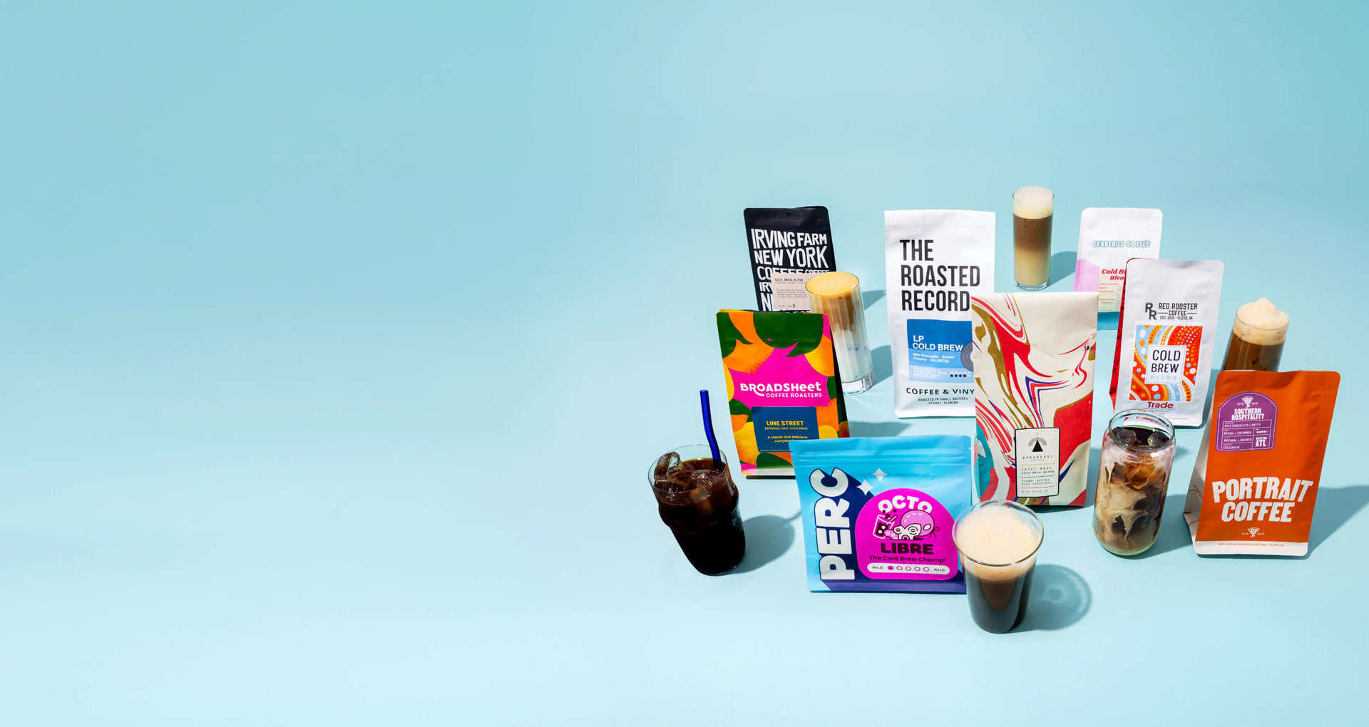 Bags of cold brew, a cold brewer, and a glass of cold brew displayed over large ice cubes